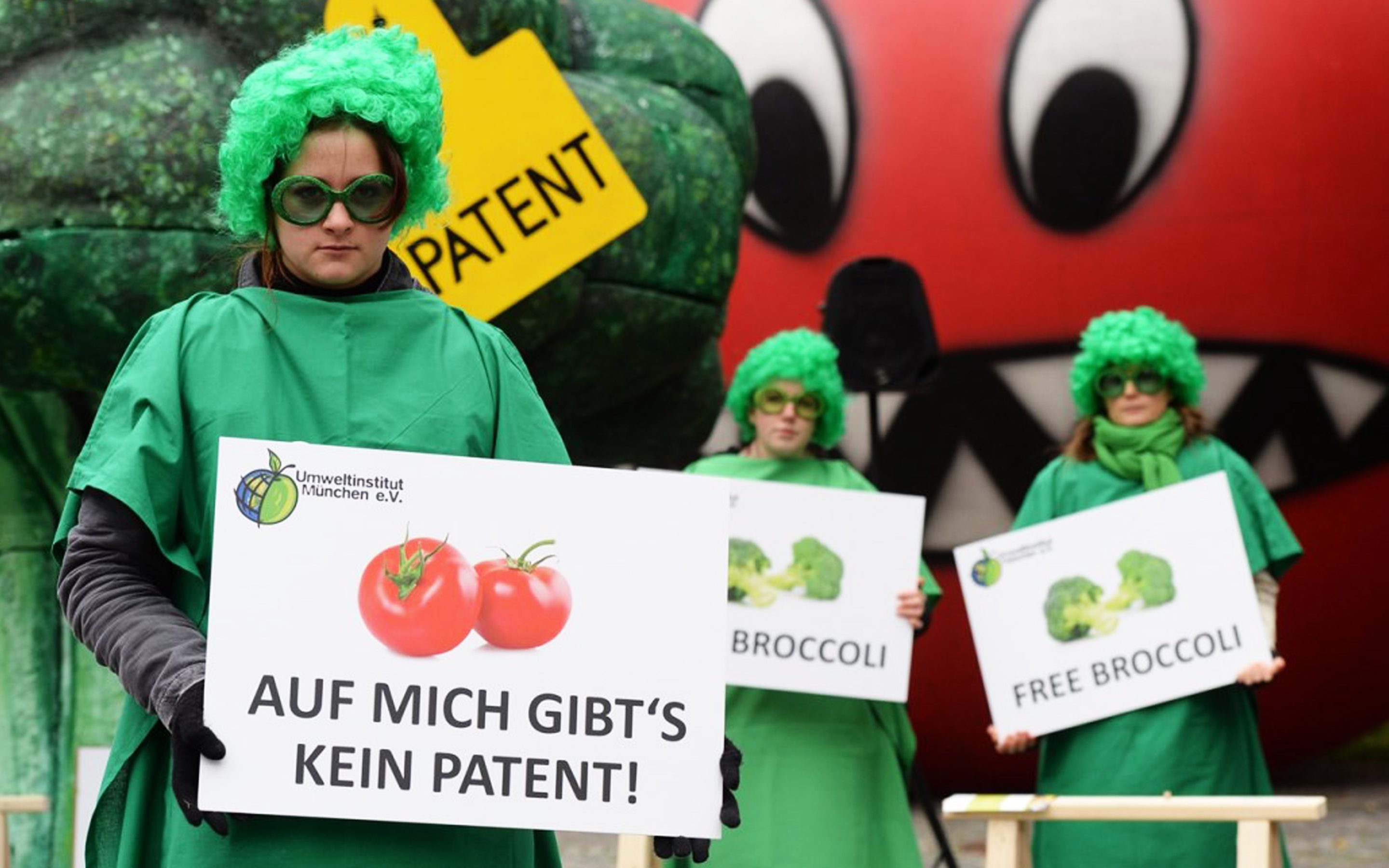 Demonstration mit Schildern und übergroßen Figuren von Tomate und Brokkoli gegen Patente auf Pflanzen im Oktober 2014