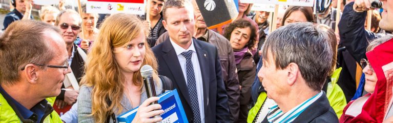 Demonstrantin interviewed Sprecherin zu Fracking und ist von Demonstrant:innen umgeben.