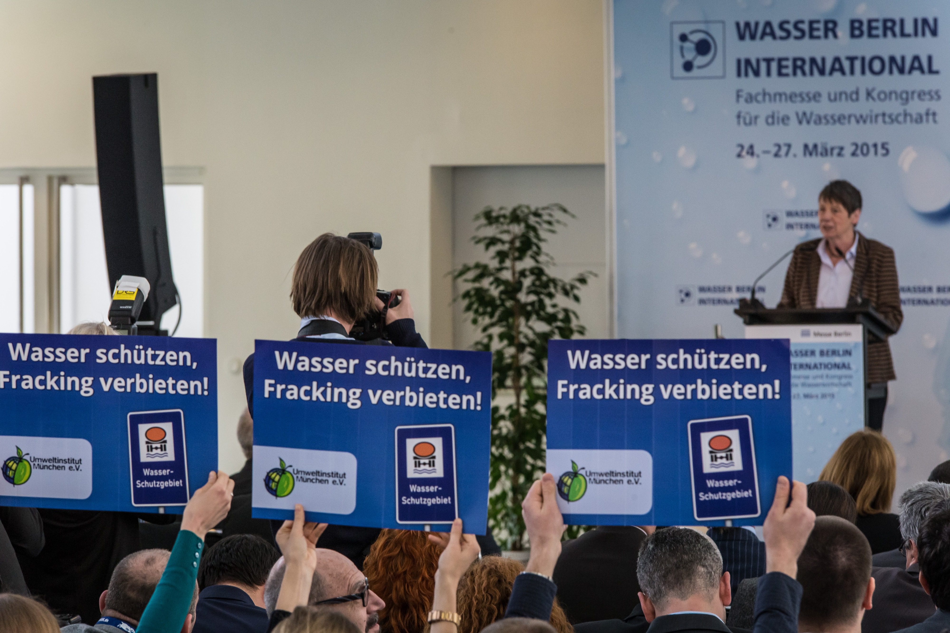 Rednerin bei Fachmesse und Kongress für Wasserwirtschaft in Berlin im Jahr 2015 vor Demonstrant:innen und Fotograf:innen.