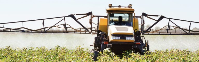 Zu sehen ist ein großer Traktor auf einem genveränderten Baumwollfeld