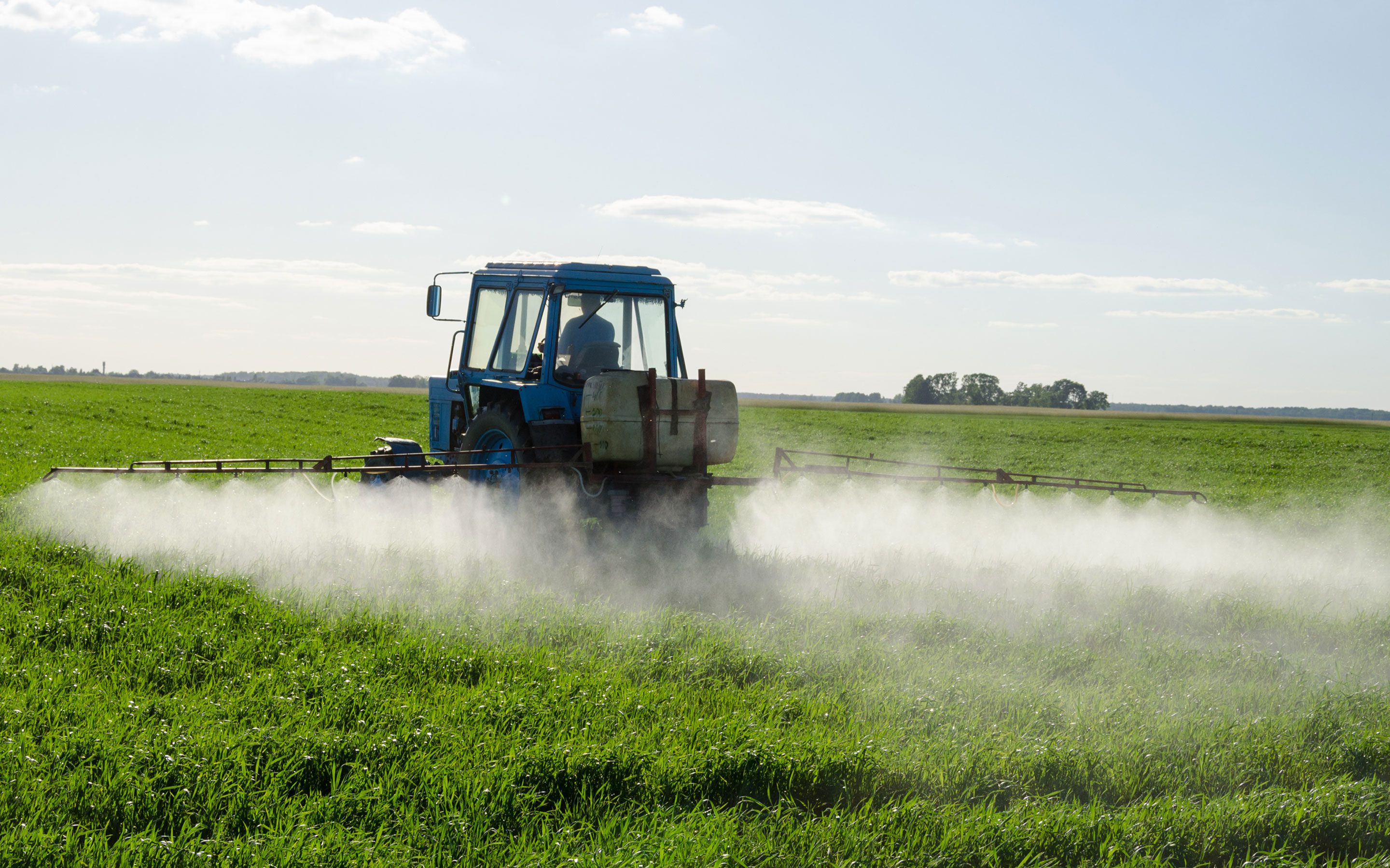 Traktor bringt Pestizide auf Feld aus