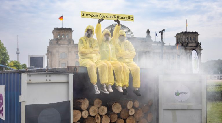 Aktivist:innen protestieren auf einem dampfenden Seecontainer vor dem Bundestag gegen den Einsatz des Klimagiftes Sulfurylfluorid