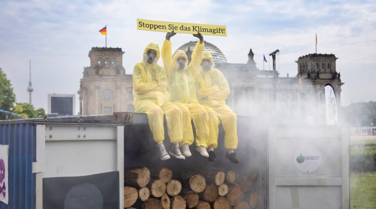 Aktivist:innen protestieren auf einem dampfenden Seecontainer vor dem Bundestag gegen den Einsatz des Klimagiftes Sulfurylfluorid