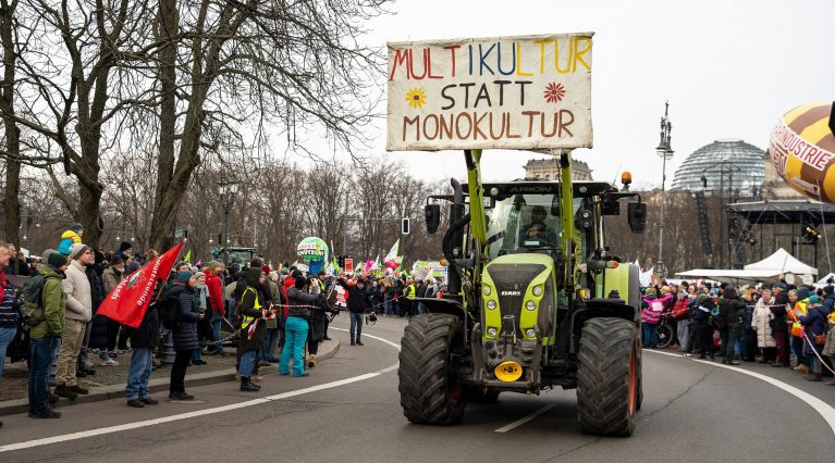 Ein grüner Traktor, der das selbstgemalte Schild mit der Aufschrift 