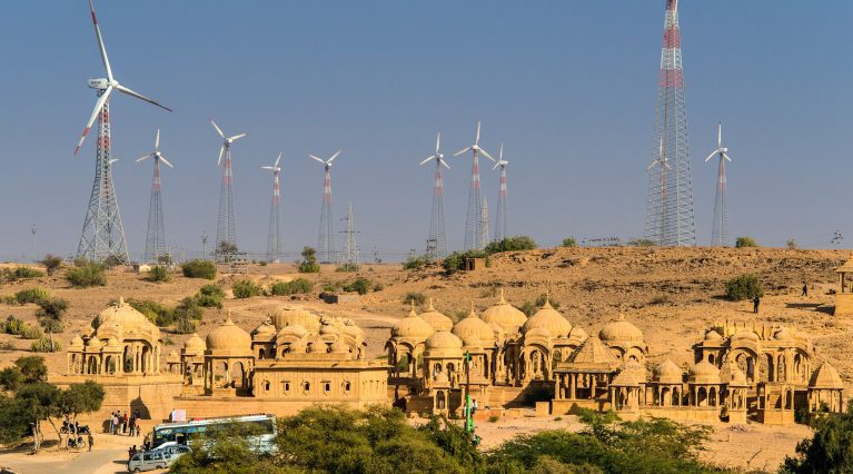 Sandsteinbauten in der Wüste von Jaisalmer vor einer Reihe moderner Windkraftanlagen. Sandsteinbauten in der Wüste von Jaisalmer vor einer Reihe moderner Windkraftanlagen.