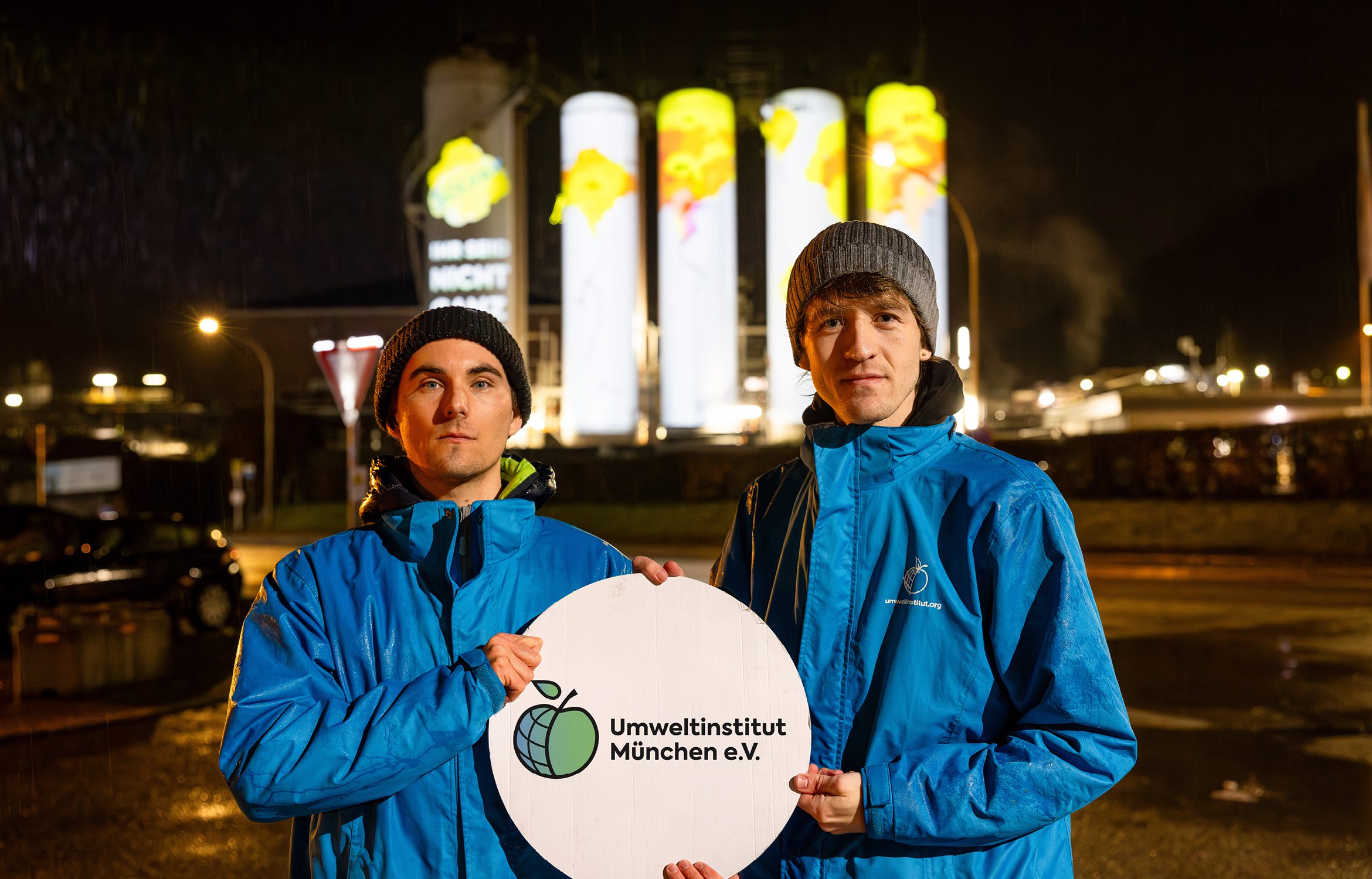 Klimateam des Umweltinstituts vor Projektion von Rissen und Spruch Ihr seid nicht ganz dicht auf Tanks der Solvay Chemiefabrik